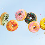 Various colorful doughnuts in motion on blue background