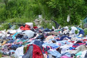 Garbage dump in nature. Environmental pollution. Abandoned clothes in nature